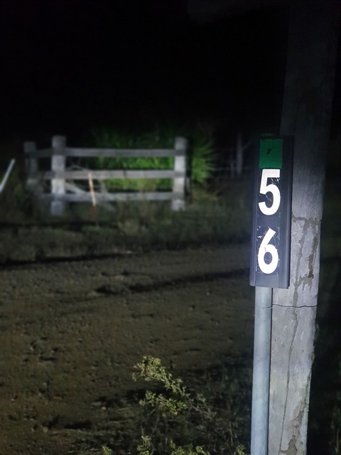 Rural address post reflecting in the light at night