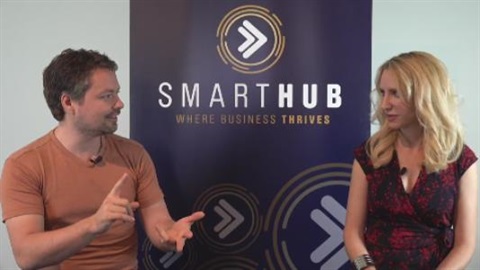 Photo of Daniel Johnsen talking to Elize Hattin with the SmartHub banner behind them